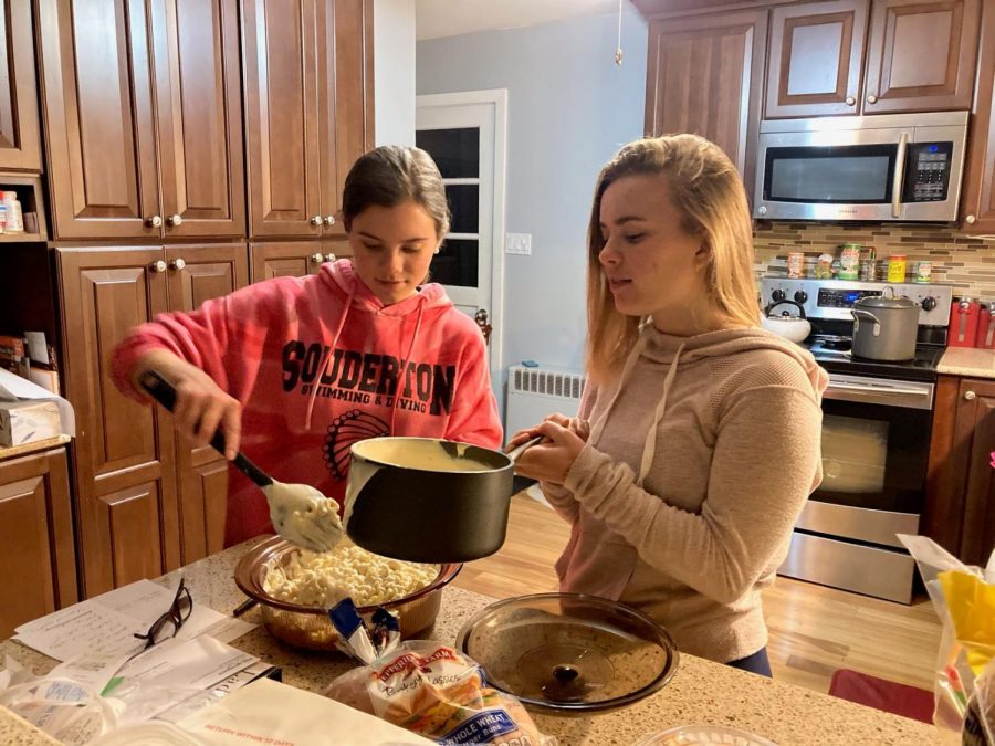 Mixing it up...Pouring the cheese, Souderton alumna Juliana Alderfer (Right) helps sister Jamie Alderfer make Mac and Cheese. The Mac and Cheese meal kit was purchased from Thirsty Dice. 