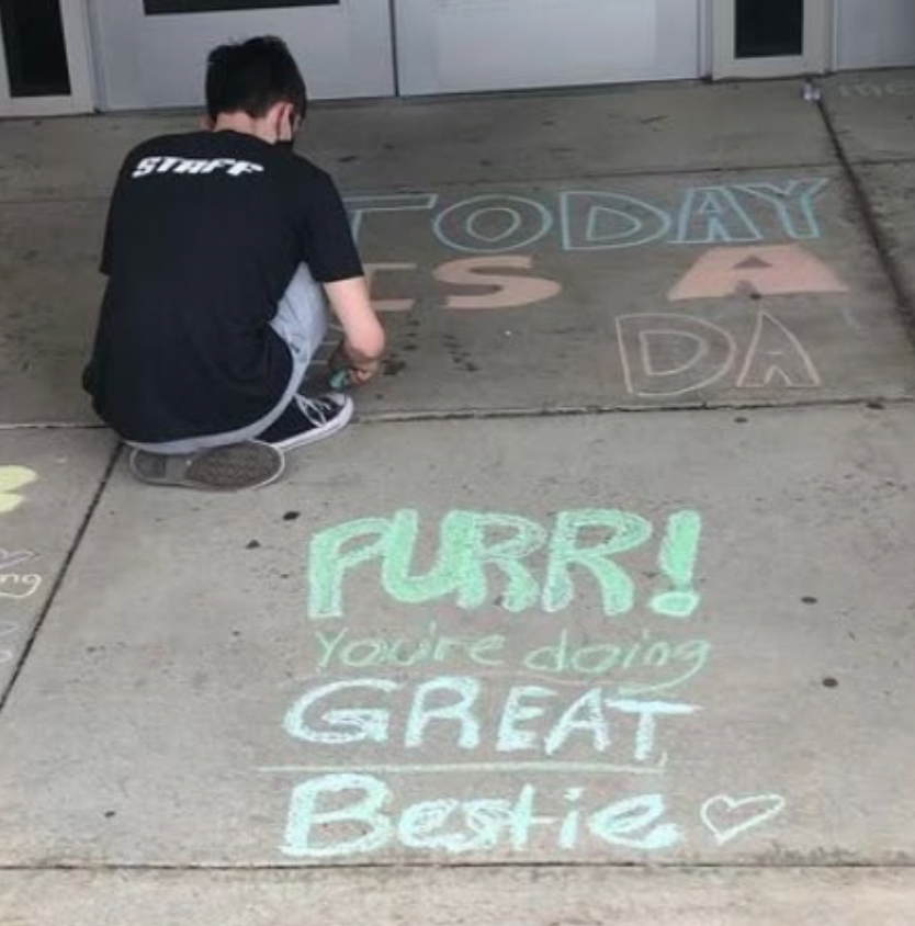 ***Creating a masterpiece...**Drawing on the pavement, junior Connor Magee is using chalk to display uplifting messages for mental health awareness month. The Peyton Heart Project club is spreading awareness of mental health in different ways such as this. Photo by Taylor Burke*
