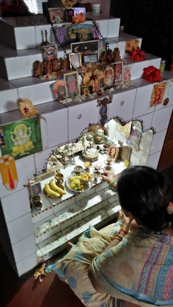 In celebration of Diwali…Offering food, freshman Anuhya Vemagiri’s grandmother Madhubala Bhaganagarapu kneels before the altar that has many Hindu gods on it. 