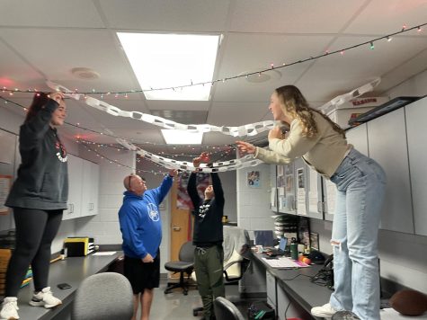 Deck the halls… Preparing for the holiday season, (left to right) junior Kate Kelcy, physical education teachers Michael Childs and Josh Wagner and sophomore Molly Kreag decorate the physical education office. They set up streamers and lights to reflect the holiday spirit. 