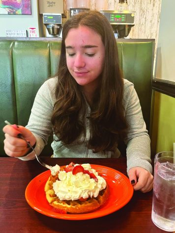 Eyes on the prize…Focusing on the food rather than her date, senior Julia Vizza enjoys a gluten-free waffle topped with vanilla ice cream, strawberries and whipped cream. Vizza indulged in this sweet meal at the Energy Station in Harleysville.