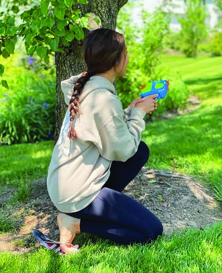 Sneak attack…Getting ready to assassinate her target, senior Peyton Krebs takes cover 
behind a tree. During Senior Assassin, many participants found hiding places to avoid being 
seen by their target or their families.