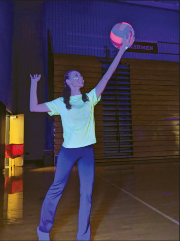 Ready, set, glow…Getting ready to serve, junior Emily Rychlak glows brightly under the black lights. Student Council hosted its annual Glow Volleyball Tournament on April 18.