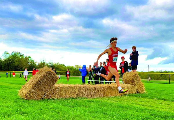 Leaping…Jumping over a hay bale, sophomore Liam Dougherty leads the pack at the Twilight Invitational Meet on October 7. Dougherty finished the race in second place. 