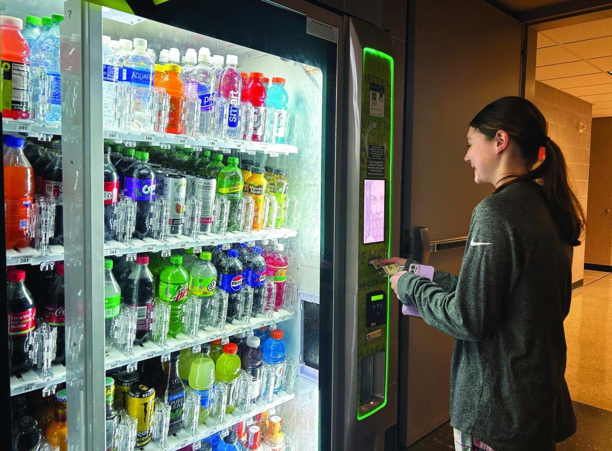 Buying a boost…Purchasing a Celsius energy drink at one of the high school’s vending machines, freshman Adelyn Besnard hopes to increase her energy for after school swim practice. 
