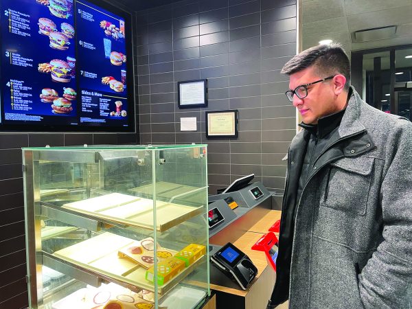 Thinking through hunger…Gazing at the food display, Souderton resident Carlos Sanchez ponders the McDonald’s menu to decide his dinner for the night. 
