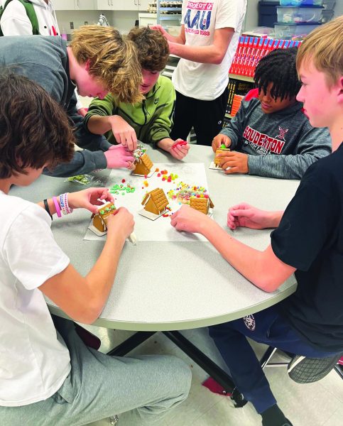 Baking a better place...Building a festive treat, (from left) sophomores Keyden Barone, Elliot Smith, Dominik Szalai, Carlos Peterson and Jackson Kelly construct gingerbread houses during the Holiday Club’s November meeting. The Holiday Club meets monthly to bake and donate treats to those in need. 