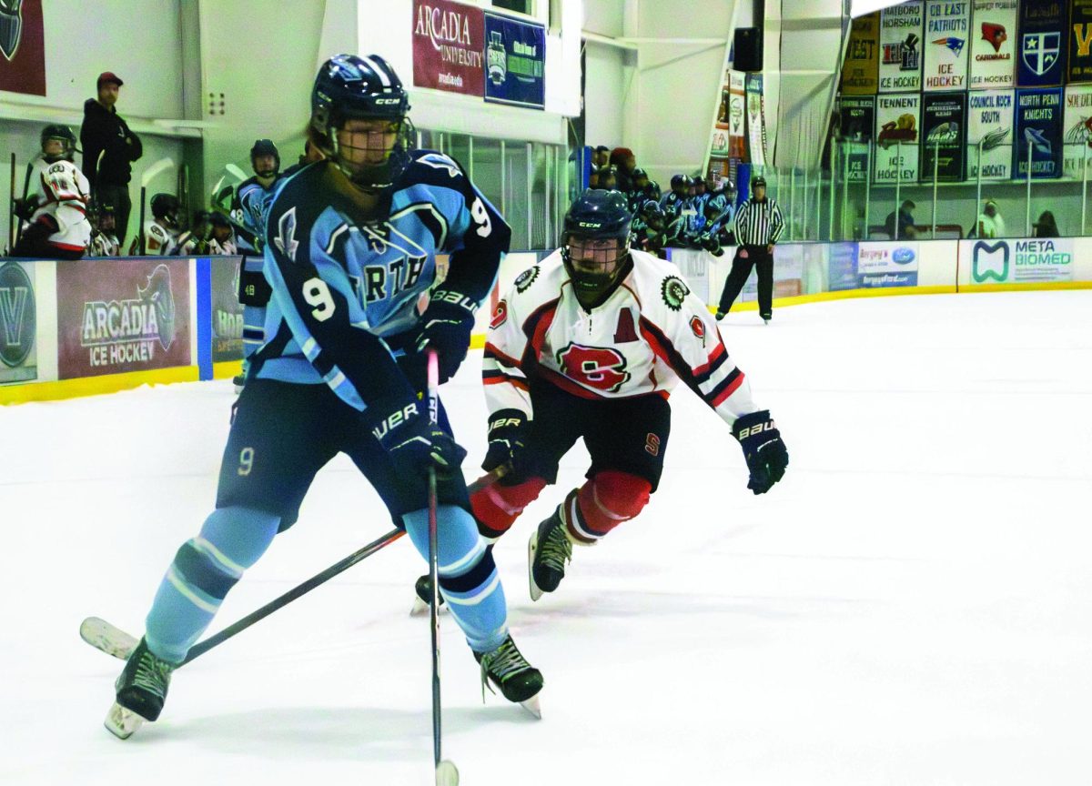 Fighting for a chance…Driving towards the puck, Souderton ice hockey player Matthew Malanga (right) strives to block North Penn ice hockey player Chase Kelly-Del Ricci from shooting a goal. 