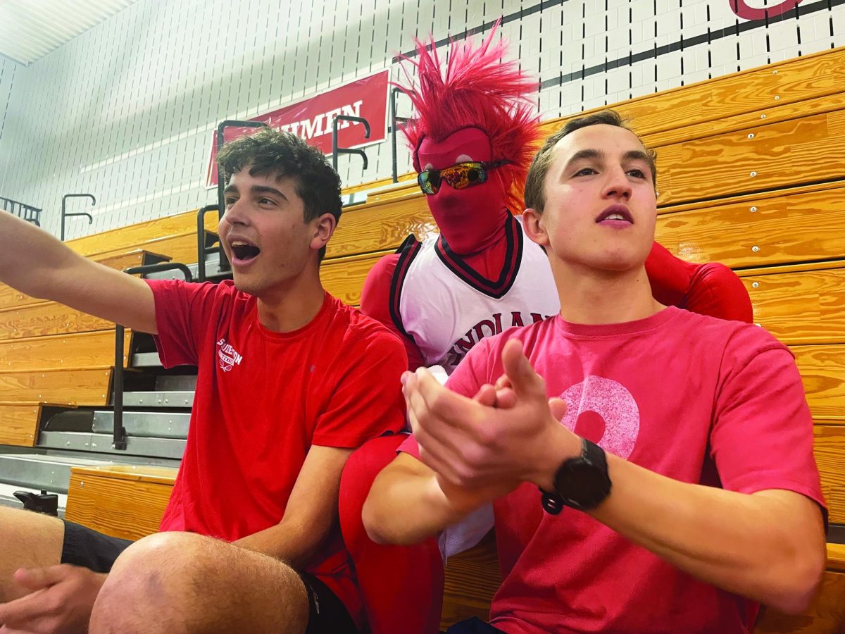 Roll Red Rebels!...Cheering for the Red Team, (from left) seniors Ryan Ciuba and James Kuduk, along with Big Red, support the Red Rebels during Gym Night on April 5.