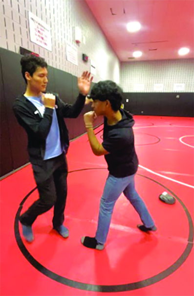 Kicking off the day… Demonstrating a new self-defense technique, club officers Colton Musselman (left) and Rohit Thomas set the scene during the April 24 club meeting. The meeting was held in the wrestling room during red zone.    