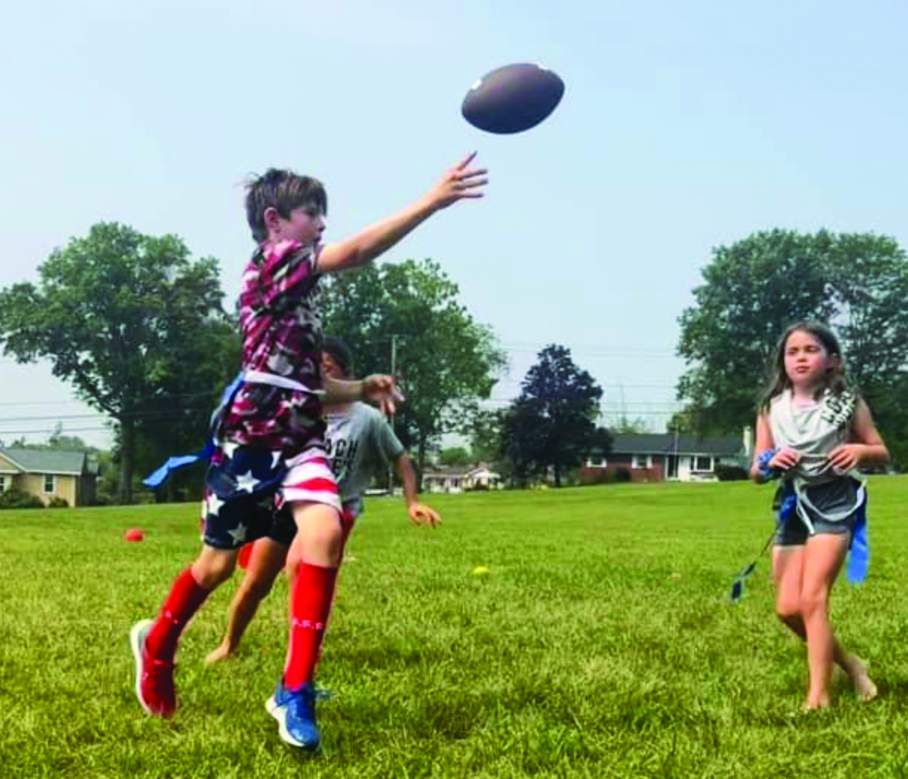 Extending the play…Avoiding a potential loss of yards, camper Xavier Morrow (left) runs away from camper McKenna Lees. Coach White’s Sports Camp offers kids an opportunity to learn a wide variety of sports and learn to play as a team.