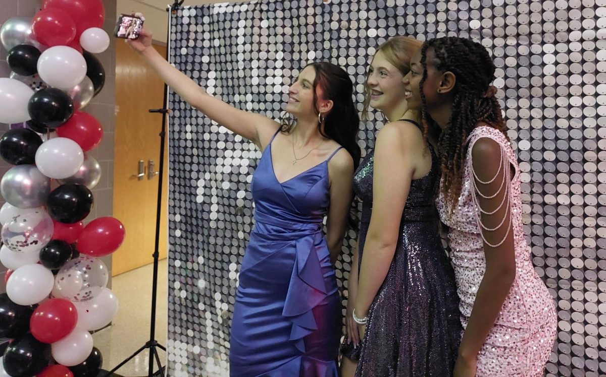 Capturing memories...During the October 5 Homecoming dance, (from left) juniors Olivia Yoder, Riannan Simpson and Zya Rota-Talarico take a break from the dance floor to document the moment.