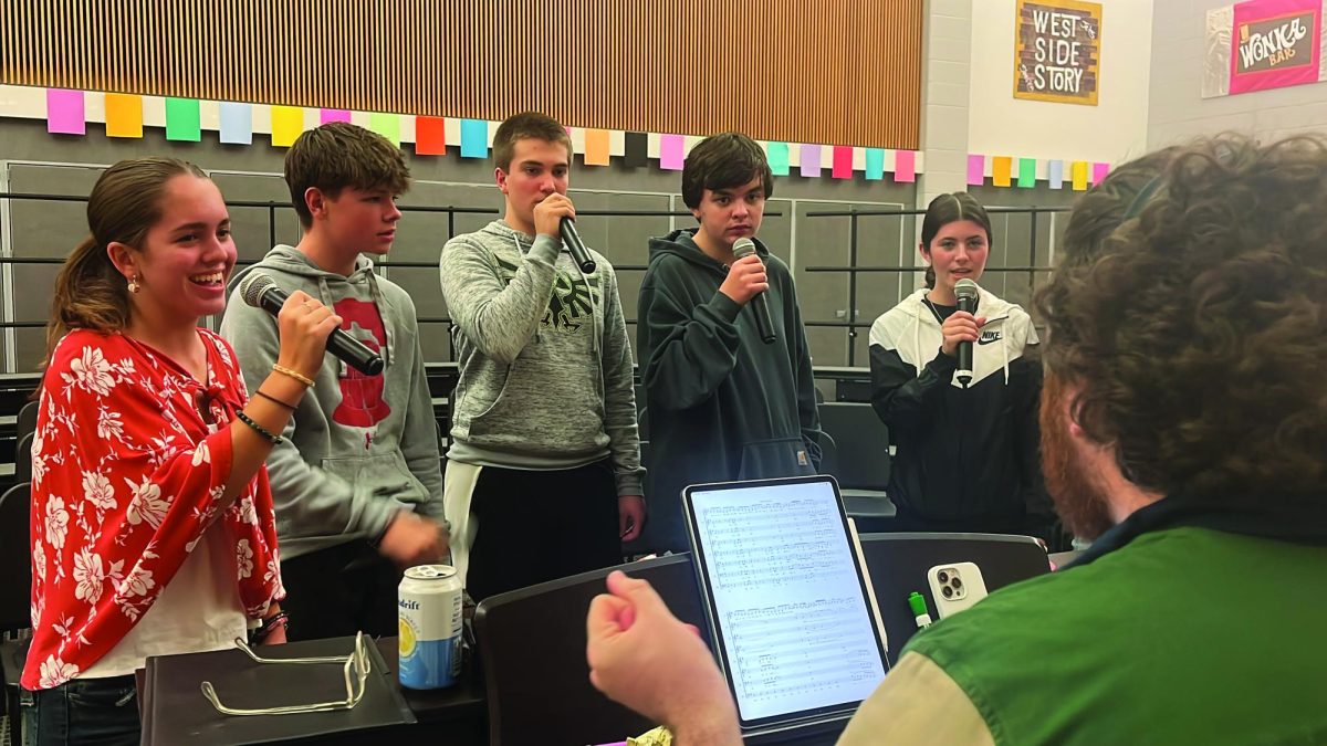 Rehearsing…During a rehearsal session, (from left) sophomore Ava Collaton-Lomas, junior Jacen Reed, sophomore Micah Perry, sophomore Jack Boell and junior Savannah Powlus sing as they prepare for the winter choral concerts on December 19 and 20. Choral director Ryan Carlin is accompanying them on the piano.