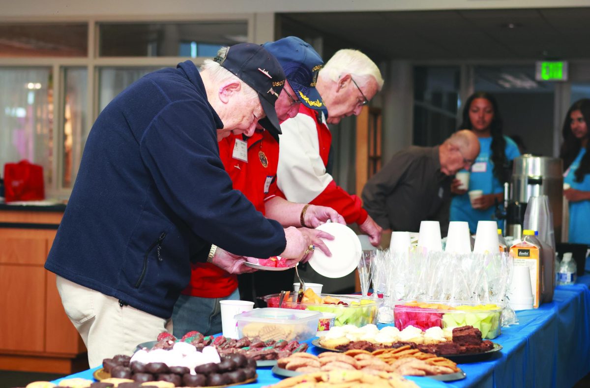 Delicious!…Enjoying the lunch buffet, (from left) veterans Bob Dell, Gordon Bell and Merril Crisman fill their plates at the Veterans Brunch on November 2. The Interact and Support Our Troops Clubs hosted the event.