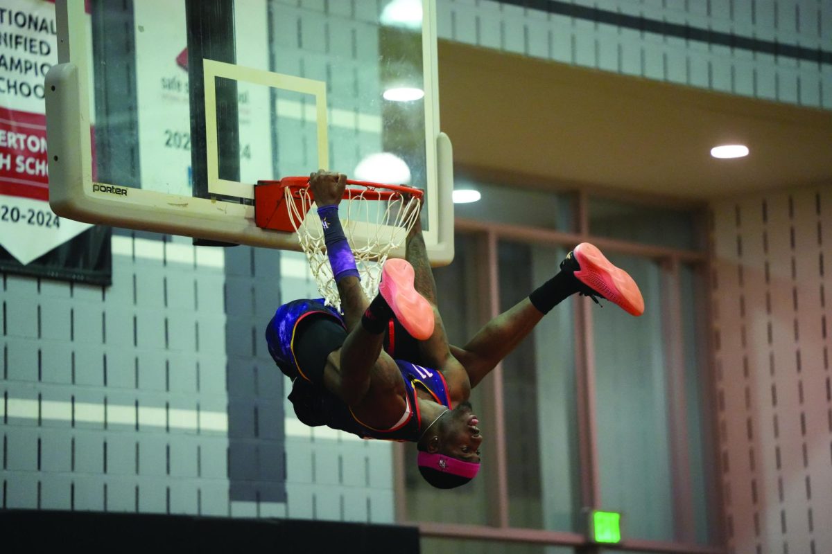 Upside down...Hanging on the rim during the pregame before the Harlem Wizards Teachers v. Wizards game, Wizards player Dragon warms the crowd up. The game took place on April 4 and lasted from 7-9 p.m.