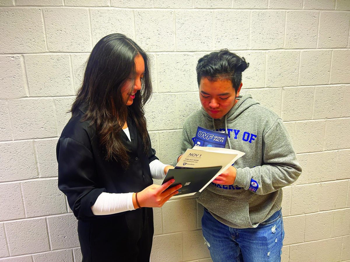 Looking ahead…Flipping through college pamphlets and brochures, sophomores Chloe Ha and Ethan Penn reflect on the information they learned while attending the spring college fair. The fair was hosted on April 10 in the main concourse.
