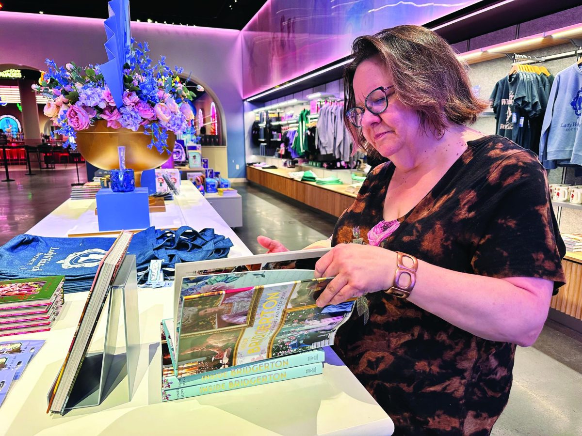 Entranced…Browsing through the book “Inside Bridgerton,” during the holiday season, visitor Kathy Miller walks through the Netflix House gift shop after playing mini golf. According to Miller, she enjoyed the gift shop and hopes “to come back next week.” 