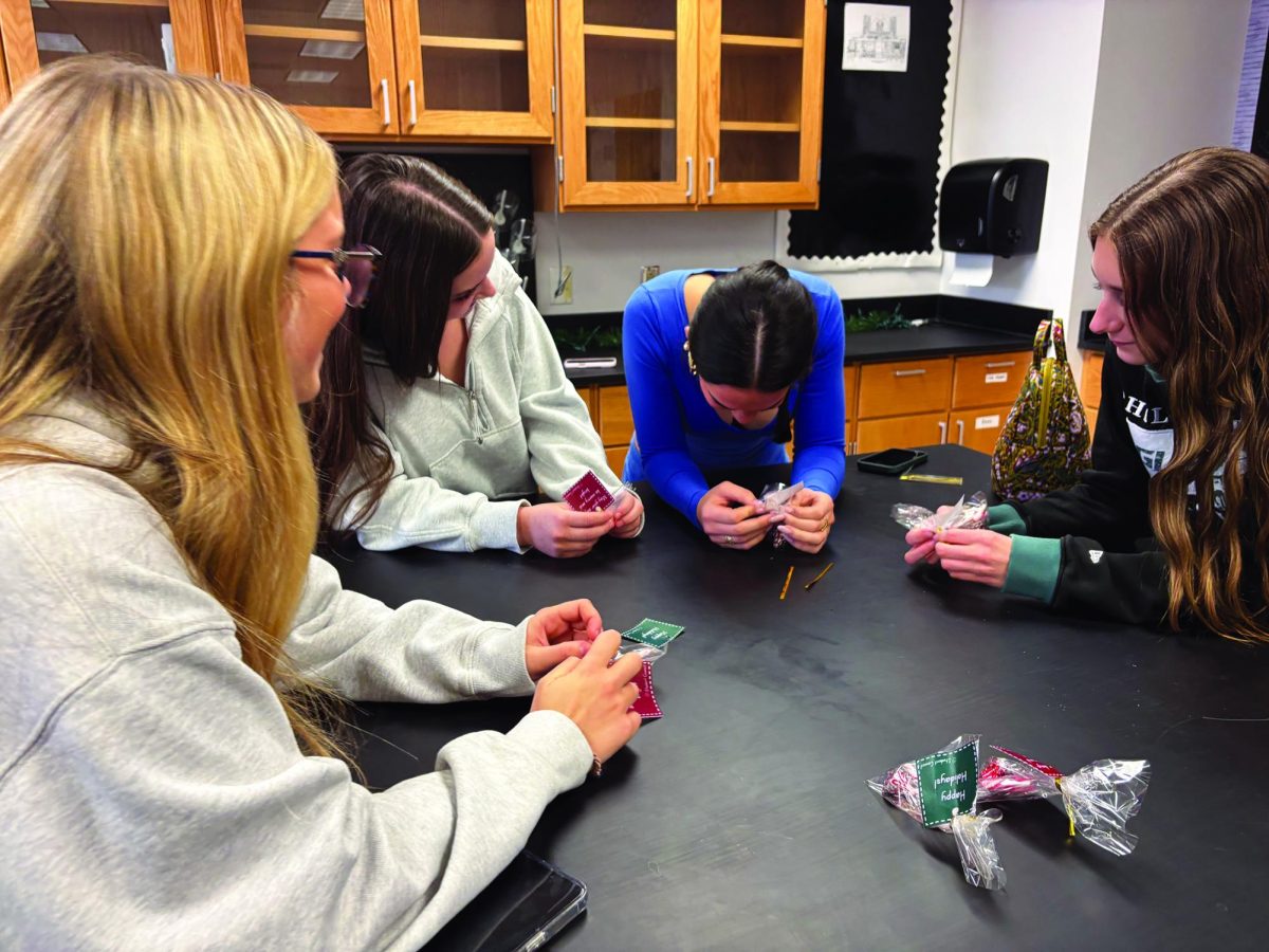 What goes around comes around…Giving back during the giving season, (from left) juniors Mia Heckman, Eva Distefano, Lily Oberst and Chloe Detweiler make goodie bags for Student Council. The bags included Hersey Kisses, candy canes and messages.