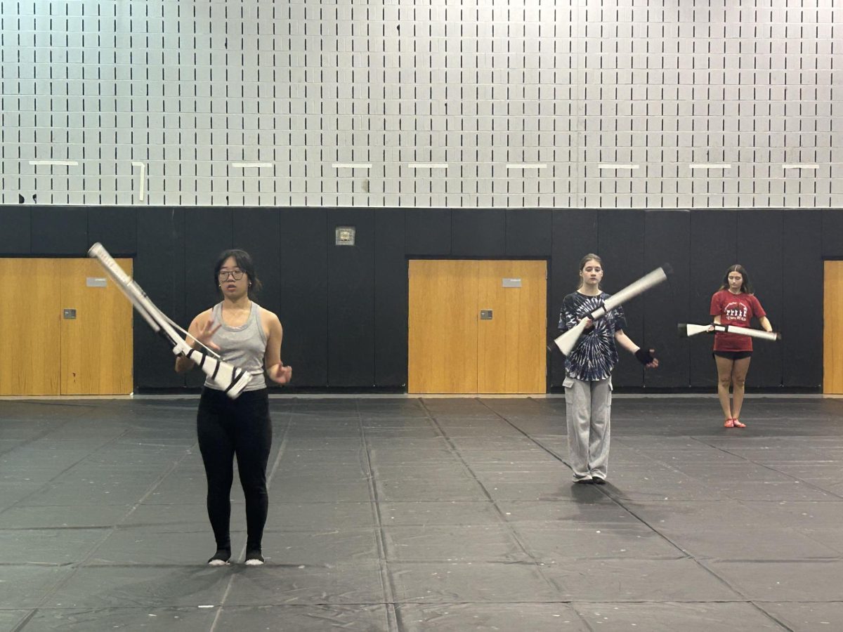 Creating Friendships . . . Working together, Sophomore Sydney Bui (left) and Senior Rose Waldron (right) practice throwing rifles during Color Guard practice. By continuing to support and encourage each other, Color Guard makes a welcoming environment for students.