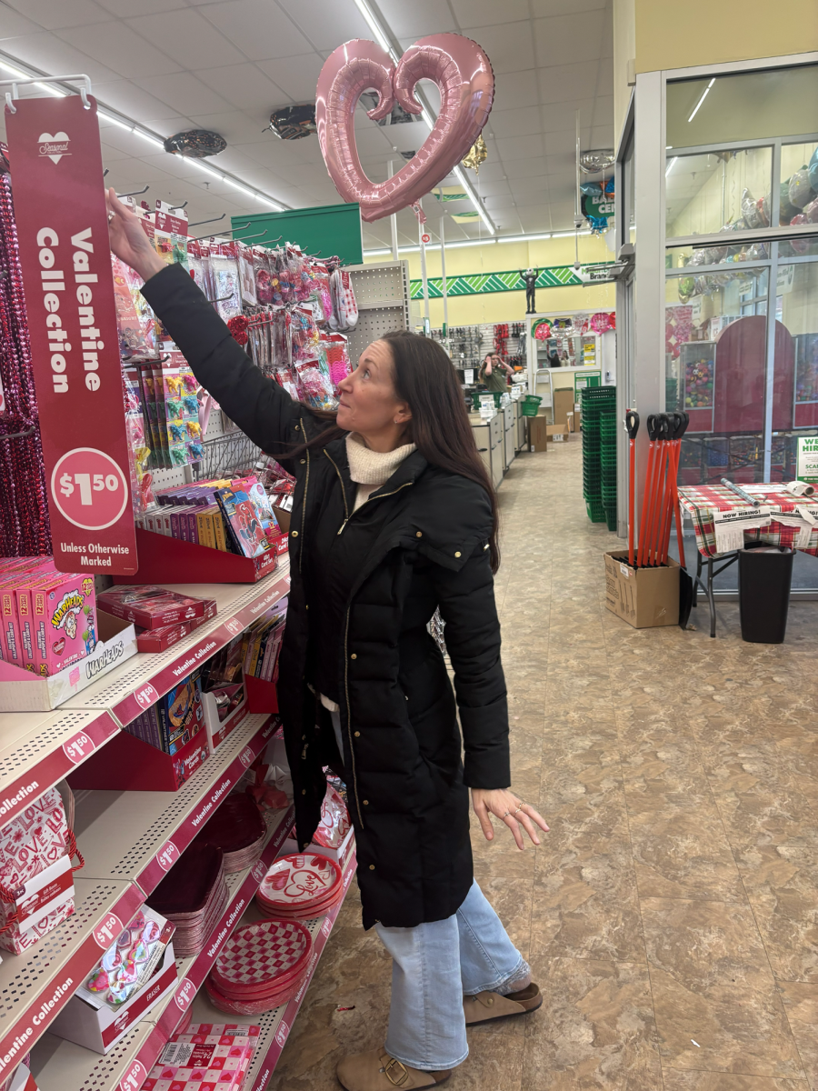 Spreading love... Reaching for the top of the shelf, Souderton resident Catherine Santiago buys Valentine's Day gifts. She bought candy and balloons for her kids.