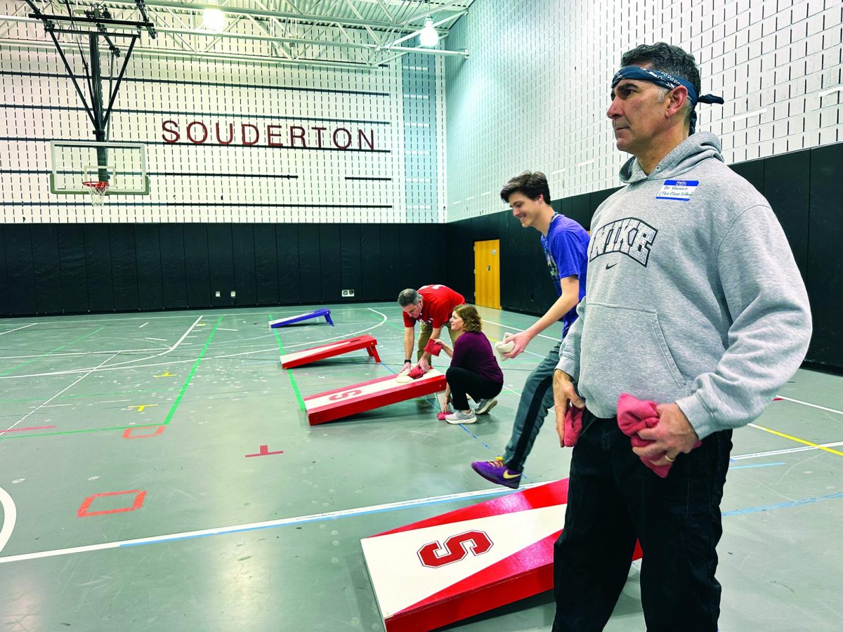 Laser focus…Looking to score 21 points, Principal Sam Varano carefully aims his beanbag before tossing it to his opponent’s board. Varano, along with his teammate, Officer Patrick Diehl, made it to the the second round before falling out of the tournament.