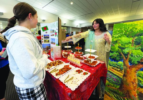 Embracing heritage...Uniting the community, sophomore Ayat Rizvi showcases her booth about her home country, Bangladesh, to sophomore Greta Chandler at the November 21 International Culture Fest.