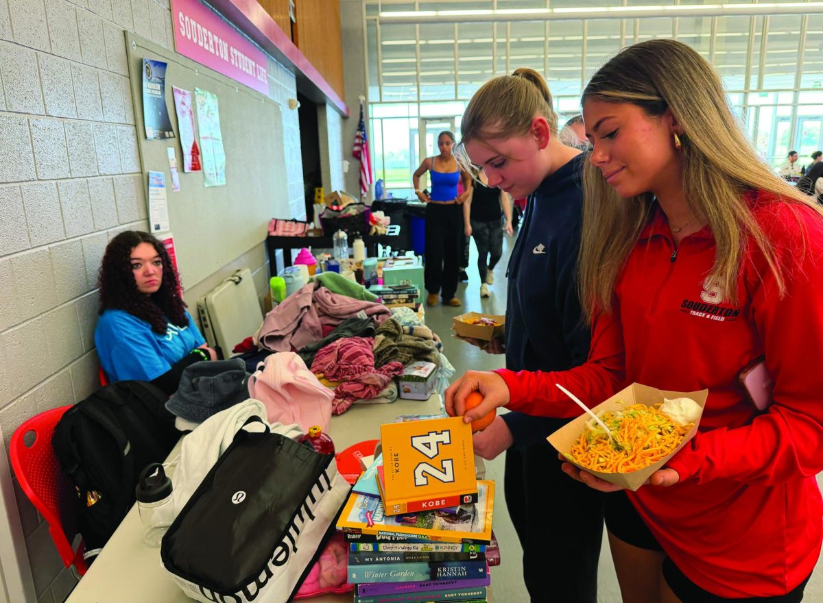 Spring cleaning...Looking at donations over lunch on April 13, (from right) seniors Kylie Hibbard and Adriana Kingsbury browse SAVE’s Buy Nothing table, manned by SAVE member Quincy McInnes.